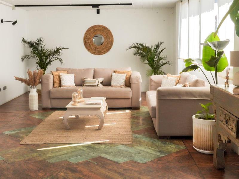 Helles Wohnzimmer mit zwei grauen Sofas, Holzboden, Pflanzen und großem Fensterlicht.