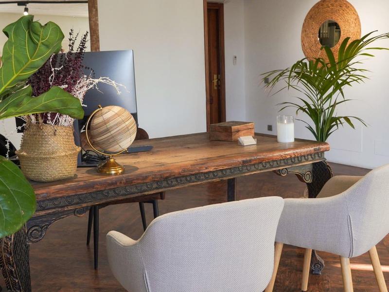 Schreibtisch mit Pflanzen, Globus und zwei hellen Stühlen in einem hellen, gemütlichen Raum.