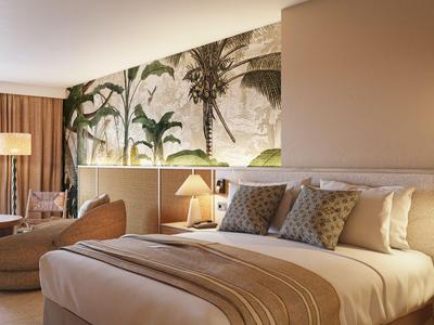 Modernes Hotelzimmer mit großem Bett, gemütlichem Sitzbereich und neutraler Farbgestaltung.