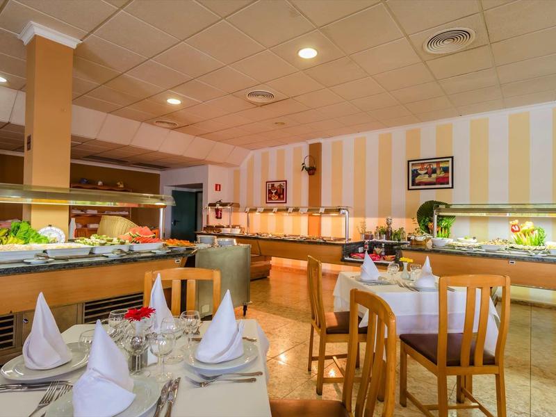 Ein helles Restaurant mit gedeckten Tischen, Buffet und gestreiften gelben Wänden.