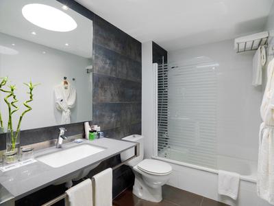 Modernes Badezimmer mit Doppelwaschbecken, Toilette, Badewanne und Glas-Duschwand.