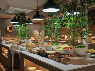 Großes Buffet mit verschiedenen Speisen, Pflanzen und modernen Lampen in einem stilvollen Raum.