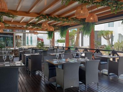 Moderna terrazza esterna coperta di un ristorante con tavoli apparecchiati e piante.