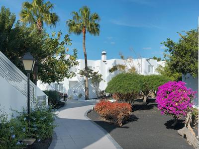 Piccolo giardino con alberi e un edificio bianco sotto il cielo blu.