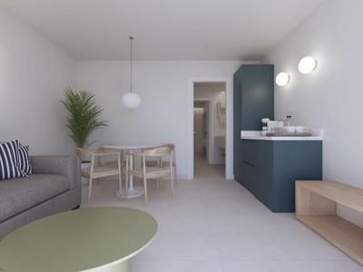 Modernes Hotelzimmer mit Sofa, Esstisch, Kochzeile und Wandfernseher.