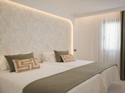 Modernes Hotelzimmer mit großem Bett, weißen Wänden und sanfter Beleuchtung.