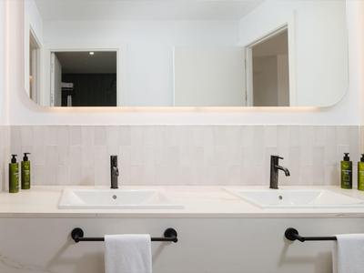 Moderner Doppelwaschtisch im Badezimmer mit weißen Wänden und zwei schwarzen Wasserhähnen.