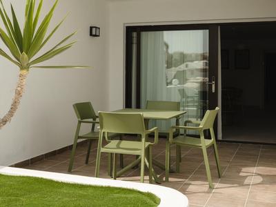 Moderner Außenbereich mit grünem Gartentisch und Stühlen neben einer Glasschiebetür.