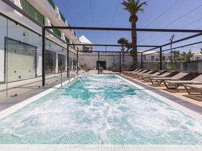 Moderner Außenpool mit Liegestühlen und Palmen in einer Hotelanlage bei klarem Himmel