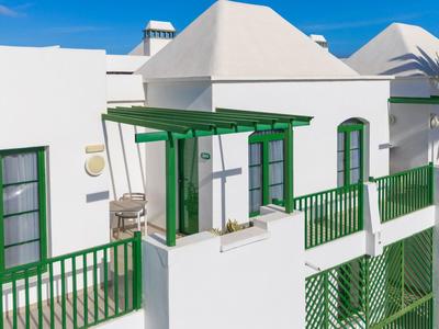 Weiße Häuser mit grünen Geländern und Fensterläden unter klarem blauem Himmel