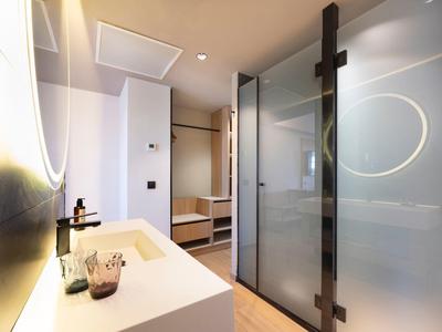 Modernes Badezimmer mit glasiger Duschkabine, beleuchtetem Spiegel und weißem Waschbecken.