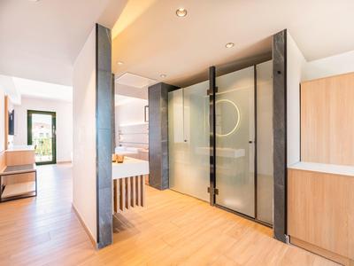 Modernes Hotelzimmer mit Dusche aus Glas und hellem Holzboden.