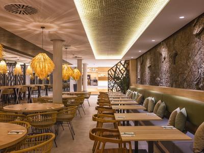 Modernes Restaurant mit warmem Licht, Holz- und Steinelementen und Sitzbereichen mit Tischen und Stühlen.