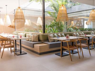 Helles, modernes Restaurant mit Holzmöbeln und großen Fenstern, das Tageslicht hereinlässt.