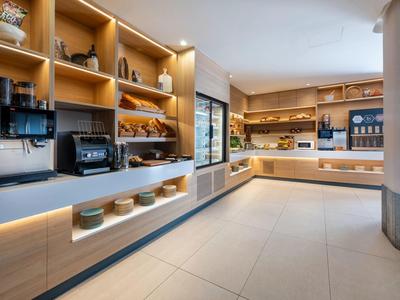 Heller Selbstbedienungsbereich mit Regalen voller Frühstücksartikel und modernen Geräten.