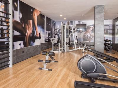 Salle de sport moderne avec haltères, appareils d'exercice et œuvres murales dans un hôtel.