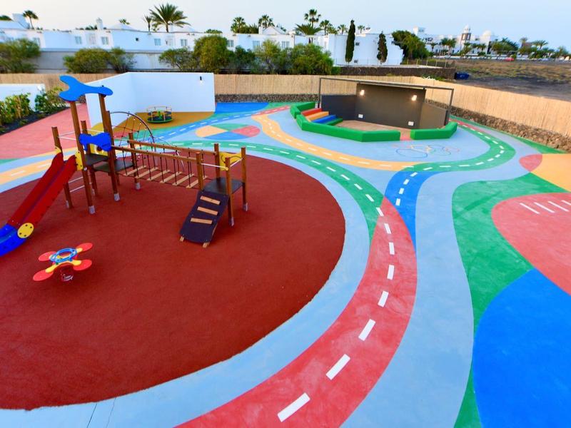 Bunter Spielplatz mit Rutsche, Klettergerüst und verschiedenen Spielflächen im Freien.