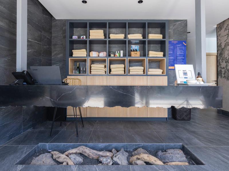 Moderner Wellnessraum mit schwarzer Steinwand, Feuerstelle und Regalen mit Deko und Licht.