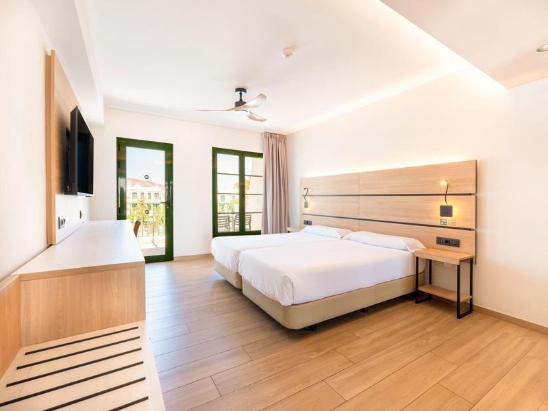 Modernes Hotelzimmer mit Doppelbett, Holzboden und Balkon mit Blick ins Freie.