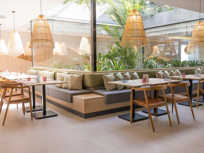 Helles, modernes Restaurant mit Holzmöbeln und großen Fenstern, das Tageslicht hereinlässt.