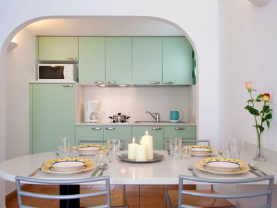 Moderne Küche mit pastellgrünen Schränken, einem Essbereich mit Kerzen und gedecktem Tisch.