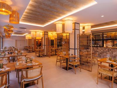 Helles, modernes Restaurant mit Holzmöbeln, warmem Licht und dekorativen Lampen an der Decke.