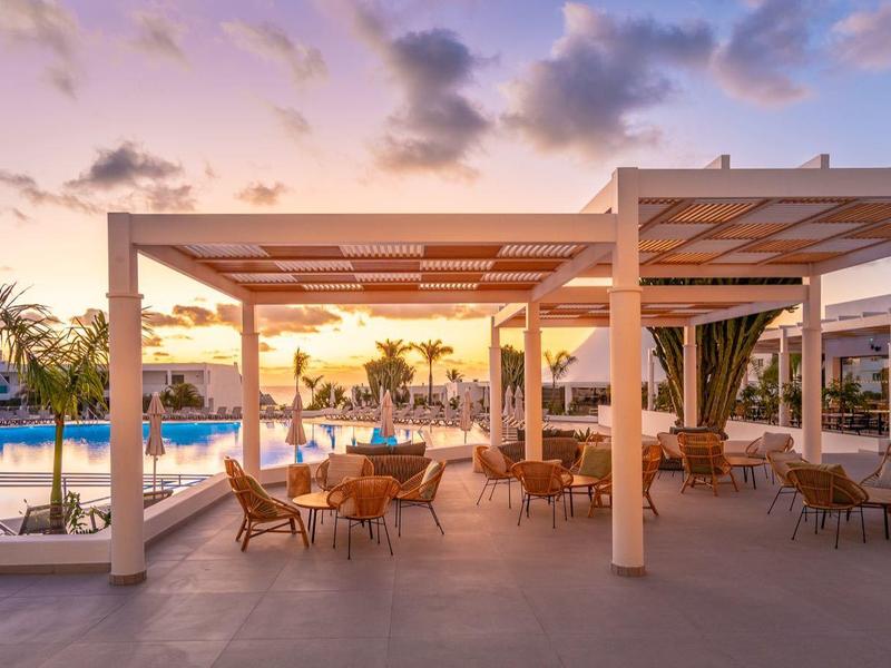 Moderner Außenbereich mit Sitzgruppen, großem Pool und Sonnenuntergangshimmel.