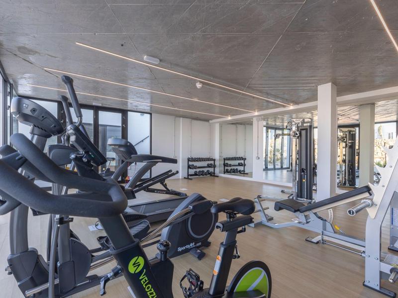 Moderner Fitnessraum mit Laufbändern, Fahrradergometern und Krafttrainingsgeräten.