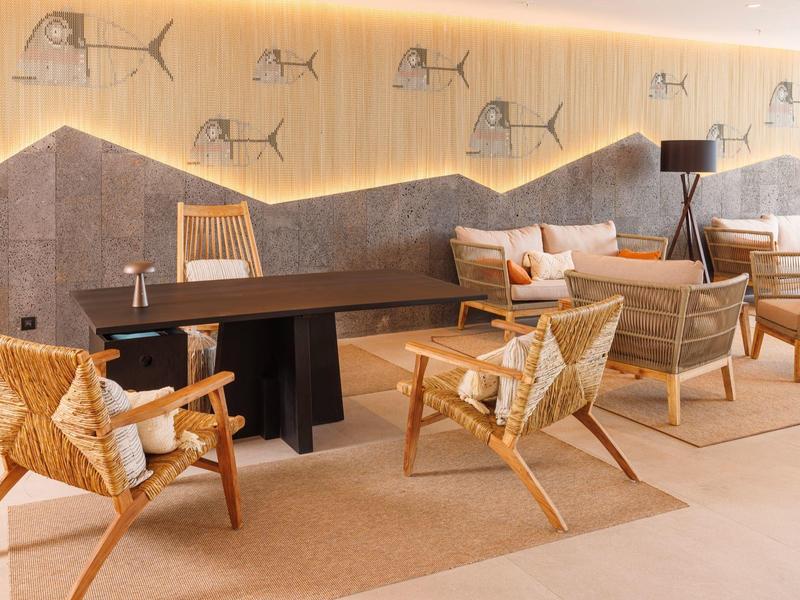 Moderner Wohnraum mit Holzmöbeln, weichen Kissen und stilvollen Fischzeichnungen an der Wand.