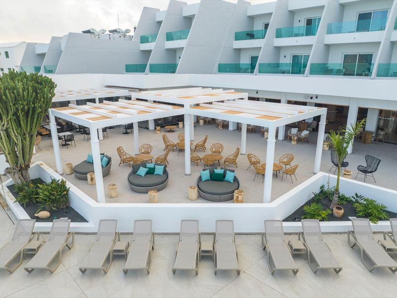 Moderner Hotelpoolbereich mit weißen Liegen, Pavillons und türkisfarbenen Sitzmöbeln.