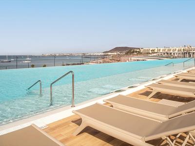 Infinity pool with lounge chairs and sea view under clear sky