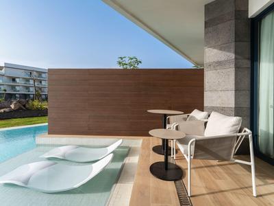 Terrasse mit modernen Liegen und Stühlen neben einem privaten Pool in der Nähe eines Hotels.