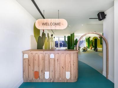 Moderner Empfangsbereich mit hölzerner Rezeption und grünen Pflanzenmotiven in hellen Farben.