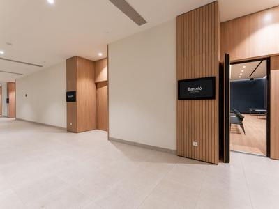 Nowoczesny, jasny korytarz hotelowy z białą podłogą i drewnianymi panelami na ścianach.