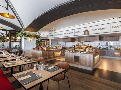 Moderne Restaurantinneneinrichtung mit Holztischen, roten Sitzbänken und großem Buffetbereich.