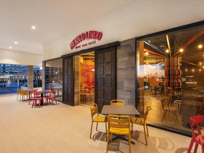 Strefa na zewnątrz nowoczesnej kawiarni z kolorowymi krzesłami i dużym oknem na wnętrze.