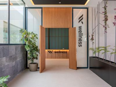 Moderner Wellness-Eingang mit Holzrahmen, grüner Polsterwand und Pflanzen links und rechts.