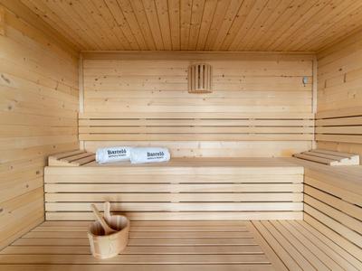 Helle Holzsauna mit zwei Liegebänken, Saunakübel, und zwei blauen Handtüchern.