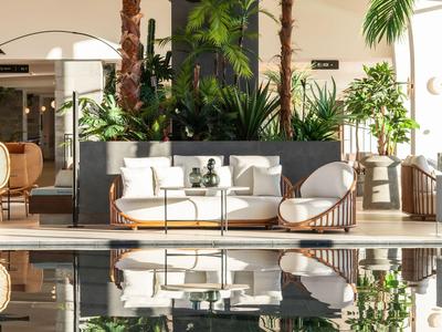 Nowoczesna przestrzeń na zewnątrz z białymi fotelami, roślinami i odbiciami w basenie.