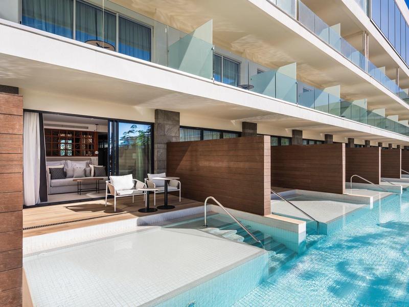 Hotelzimmer mit direktem Zugang zum Pool und moderner Außenterrasse.