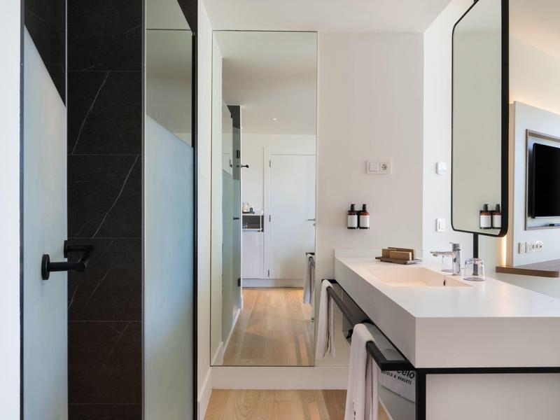 Moderner Hotelbadezimmer mit großer Dusche, Doppelwaschbecken und geräumigem Spiegel.