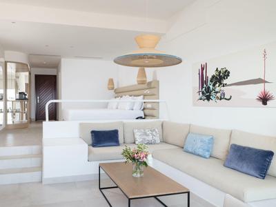 Helles Wohnzimmer mit weißem Sofa, bunten Kissen, Holz-Couchtisch und moderner Wanddekoration.