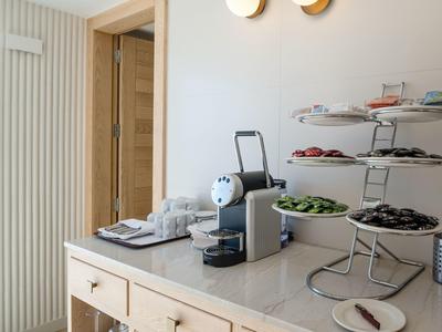 Weiße und schwarze Makkaroni, Gurken und Tomaten auf weißem dreistöckigem Servierständer in heller Küche.