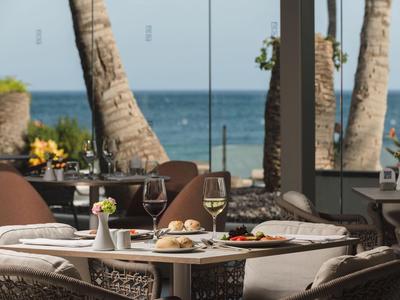Terras met gedekte tafel en zeezicht, palmbomen op de achtergrond.