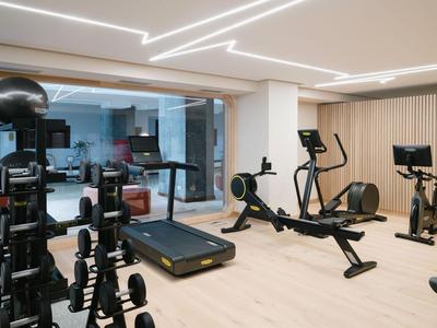 Een moderne sportschool met loopband, roeimachine en andere fitnessapparatuur voor grote ramen.