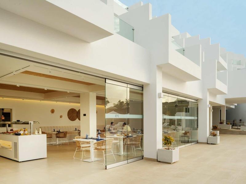 Modernes, weißes Gebäude mit großen Glasfronten und offenem Innenraum bei Tageslicht.