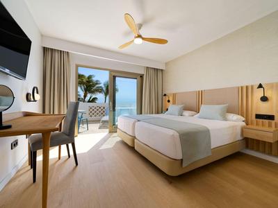 Nowoczesny pokój hotelowy z łóżkiem podwójnym, biurkiem, tarasem i widokiem na morze.