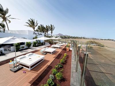 Terrasse sur le toit avec transats, parasols et vue sur un paysage côtier sous un ciel dégagé.