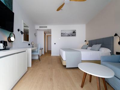 Chambre d'hôtel moderne avec lit, canapé, bureau et télévision.