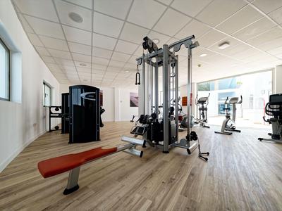 Salle de sport bien éclairée avec équipement moderne et sol en bois